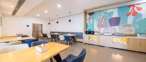 Un comedor moderno con mesas y sillas, una encimera de cocina y un mural colorido en la pared.