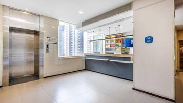 A hotel lobby with a reception desk, a vending machine, and an elevator.