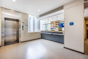 A hotel lobby with a reception desk, a vending machine, and an elevator. - Meiwu Hotel (Lanzhou Dngfanghong Square Railway Bureau Store) (Lanzhou)