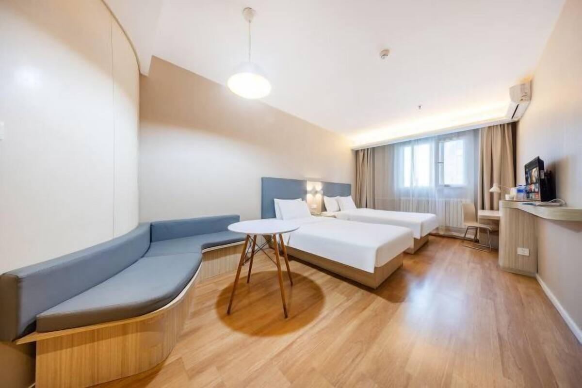 Una habitación de hotel con un sofá curvo, una cama, una mesita y un televisor.