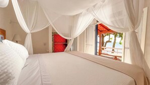 A bedroom with a bed, white curtains, and a view of the sea. - Blow Show Casa I  (Ilhabela)