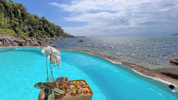 A pool with a floating tray of fruits and a potted plant. - Blow Show Casa I  (Ilhabela)