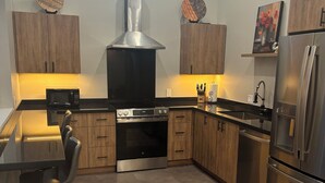 A modern kitchen with wooden cabinets, stainless steel appliances, a built-in oven, and a large window above the sink. - Dramatic New Home Right Downtown (Prescott)