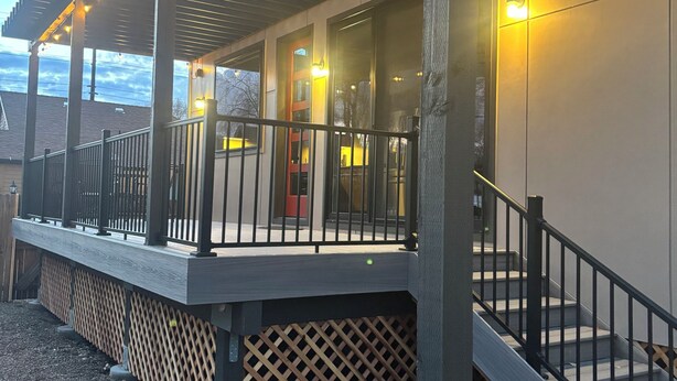A covered outdoor area with a wooden deck, metal railing, and string lights. - Dramatic New Home Right Downtown (Prescott)