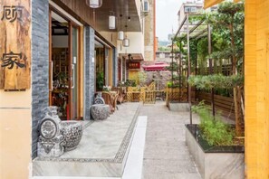 A courtyard with a pathway leading to a building entrance, outdoor seating, and potted plants. - Gujia Hotel (Kunming)