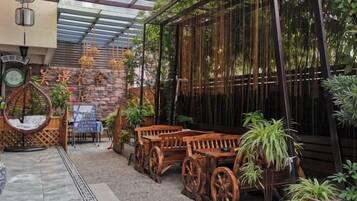 A covered outdoor seating area with wooden furniture and potted plants.