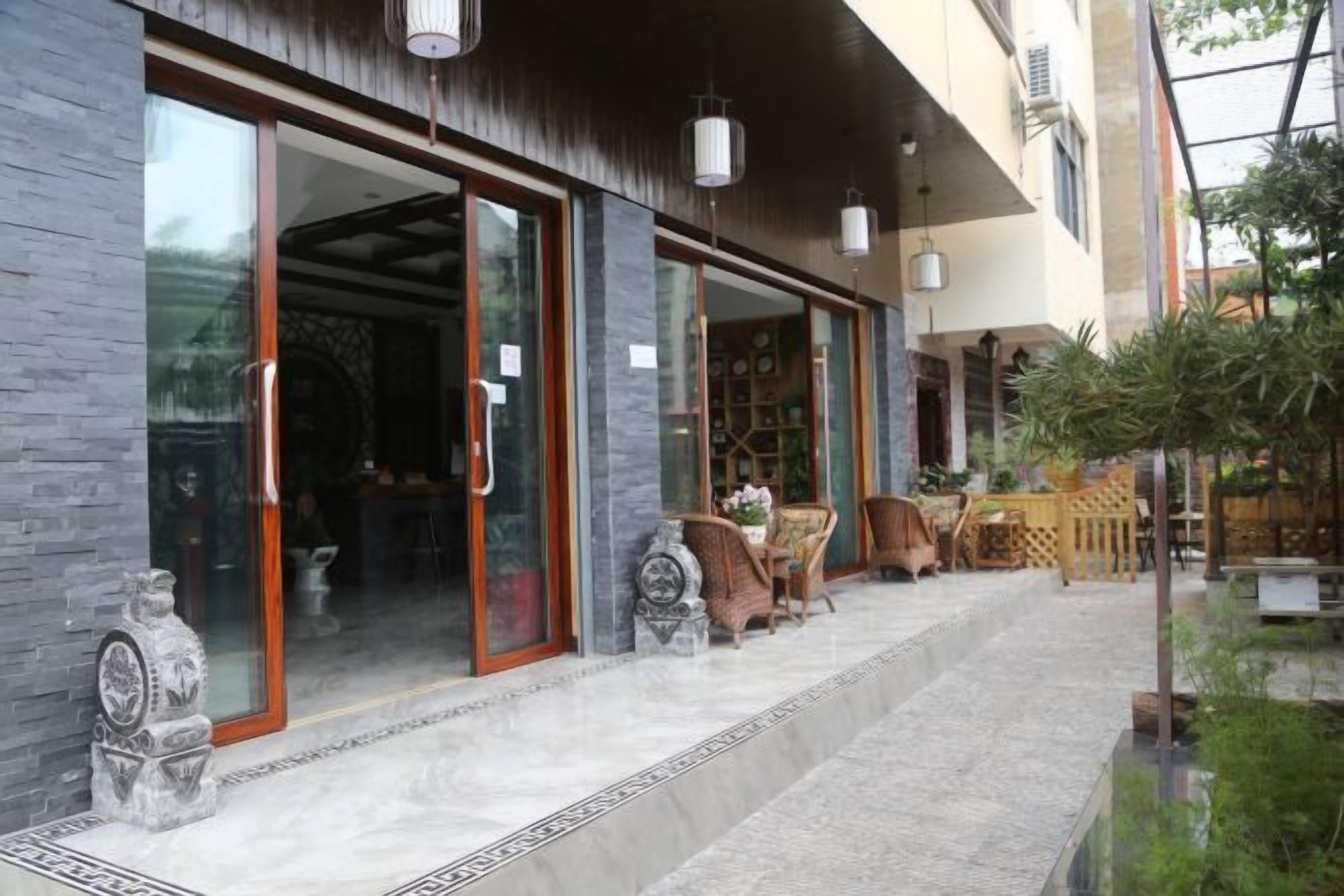 A building with large glass doors, outdoor seating, and a small garden area.