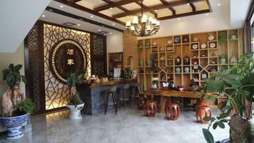 A hotel lobby with a reception desk, bar area, and a plant-filled interior.