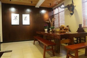 A traditional Japanese-style room with a wooden dining table, benches, and a decorative animal head mounted on the wall. - Gujia Hotel (Kunming)