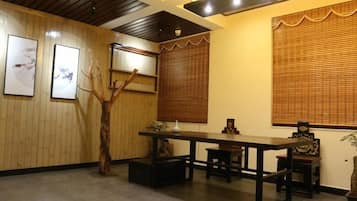 Una habitación con suelo de madera, una mesa de comedor con sillas, una planta decorativa y cuadros en las paredes.