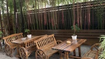 Outdoor wooden tables and benches with wheels, surrounded by a bamboo fence.