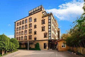 A multi-story hotel with a traditional architectural style, featuring a prominent entrance and a clear sky in the background. - Gujia Hotel (Kunming)