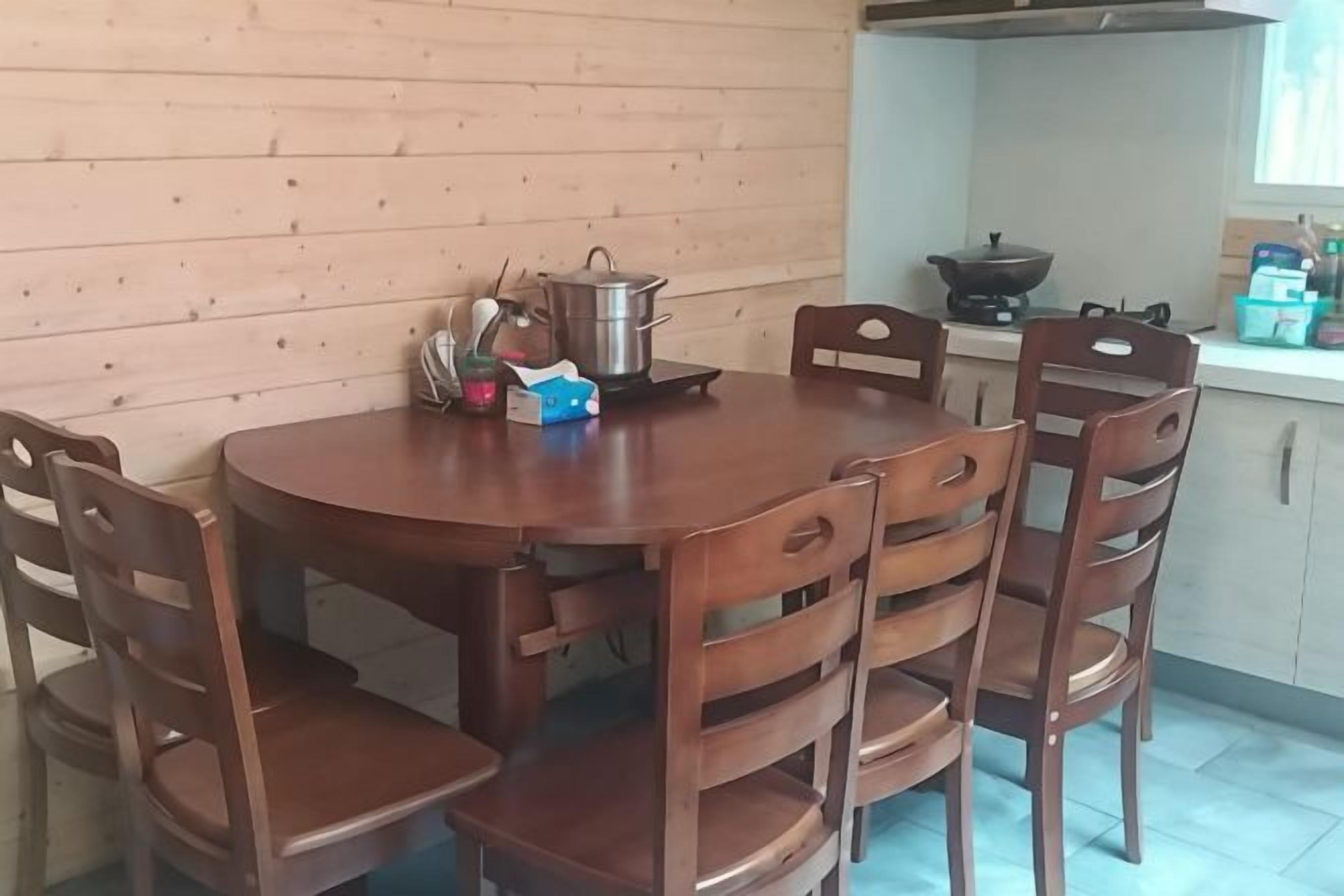 Ein Holztisch mit Stühlen, einem Topf und einer Schachtel darauf.
