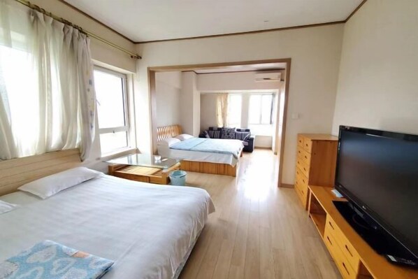 Une chambre d’hôtel avec deux lits, une télévision et un meuble en bois pour la télévision.