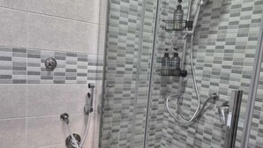 A modern bathroom with a glass-enclosed shower, a toilet, and a sink. - Clale Rooms (Naples)