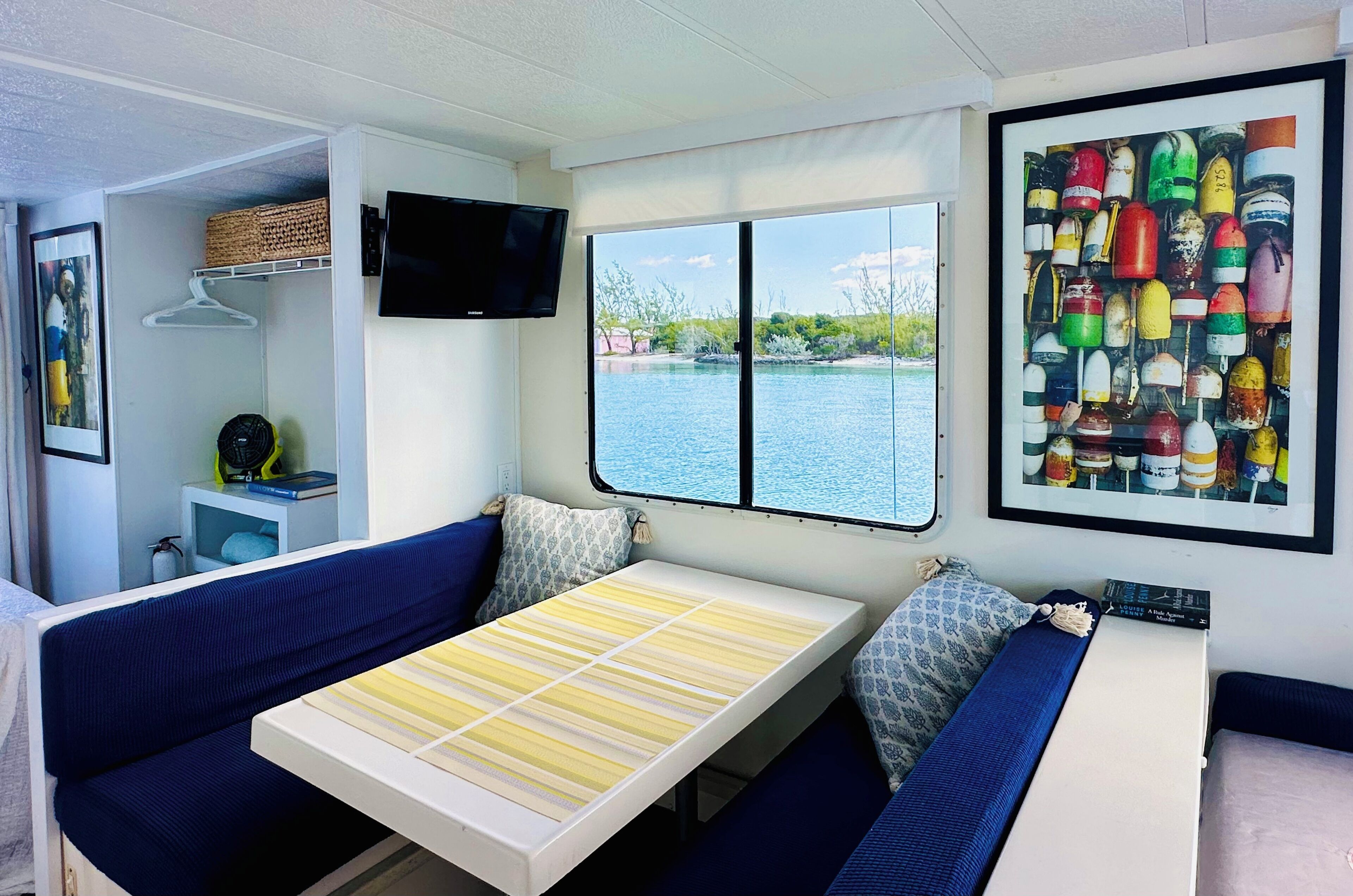A compact room with a bed, a TV, and a window overlooking a body of water.