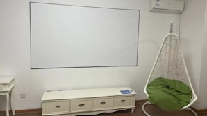 A room with a white air conditioning unit, a white dresser with drawers, and a hanging chair with a green cushion. - Yisuli Hotel (Dalian Hi-tech Wanda Plaza) (Dalian)