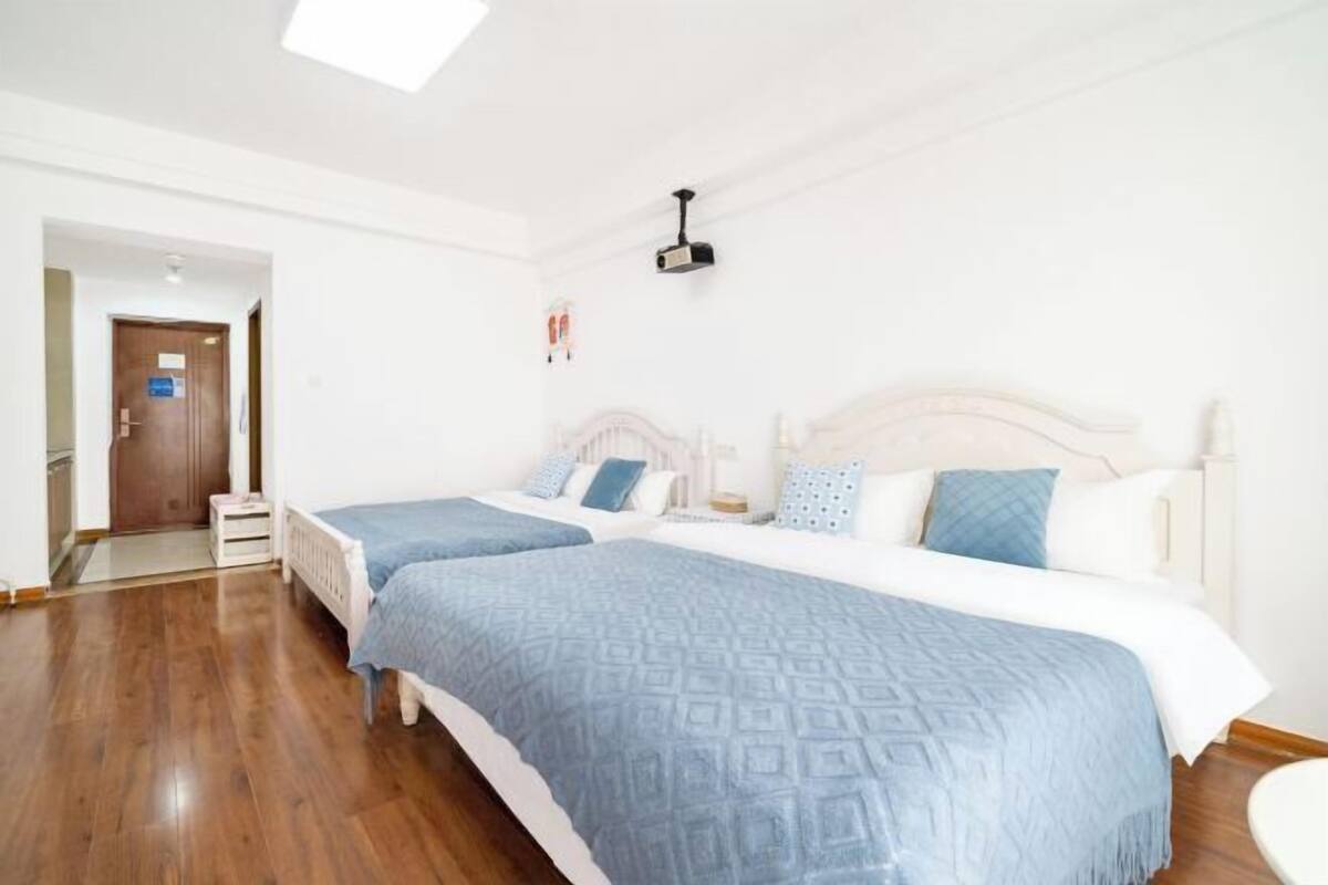 A hotel room with two beds, a projector, and a door leading to a hallway.