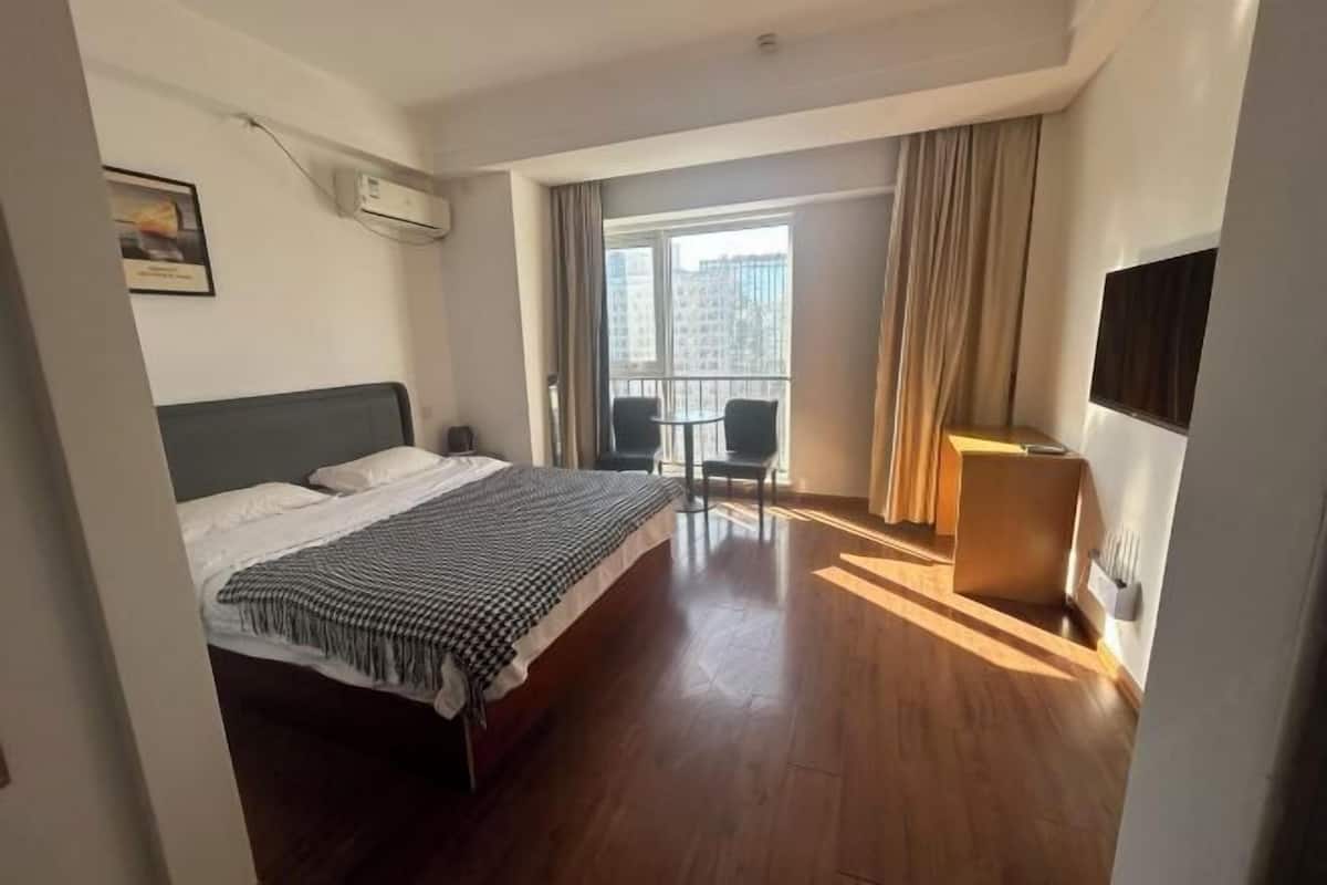 A hotel room with a bed, a desk, a chair, and a window with curtains.