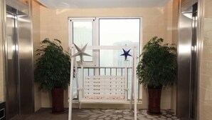 A hallway with a bench, two potted plants, and a starfish decoration. - Yisuli Hotel (Dalian Hi-tech Wanda Plaza) (Dalian)