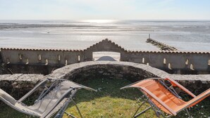 A view from a stone-walled terrace overlooking a beach with two lounge chairs facing the sea. - L'Embrun - Accès direct plage - Jardin (La Bernerie-en-Retz)