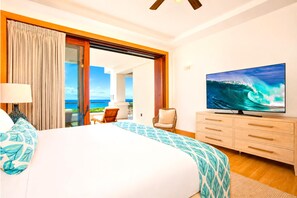 A hotel room with a bed, a television displaying a wave, a chair, and a view of the ocean.