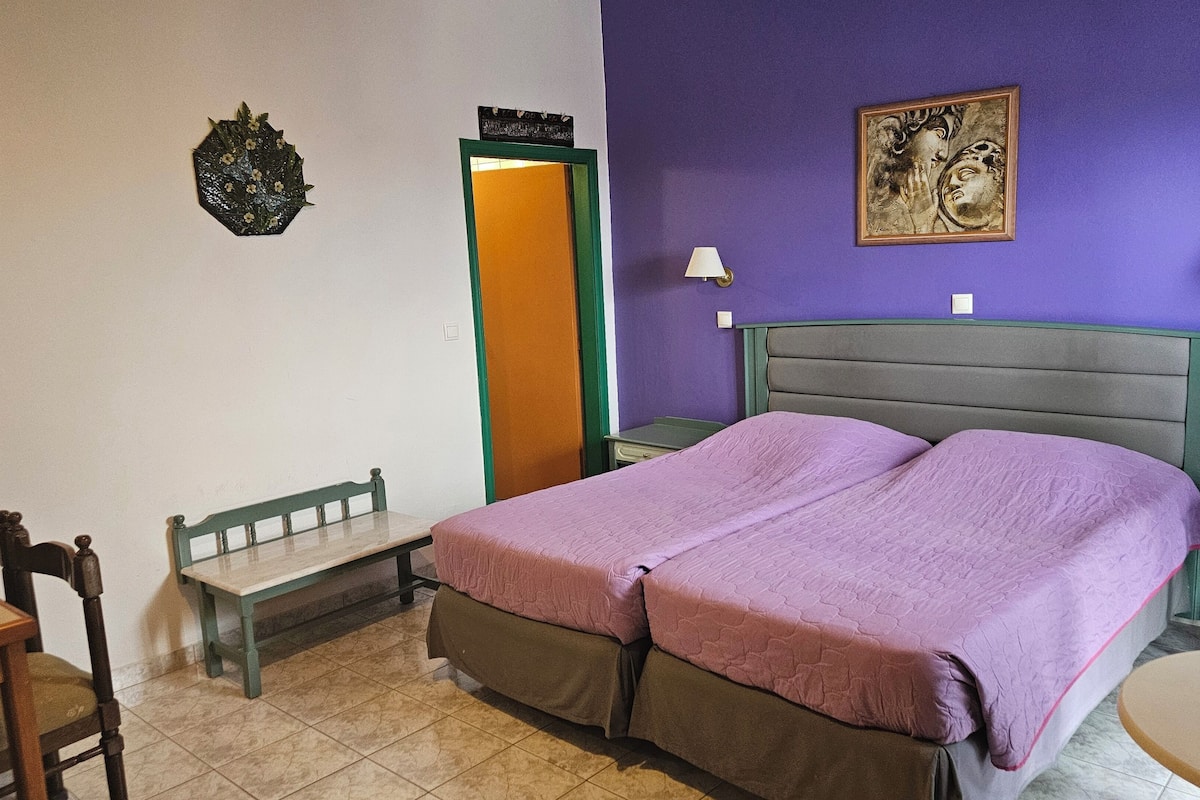 A bedroom with a bed, a bench, a nightstand, and a wall-mounted lamp.