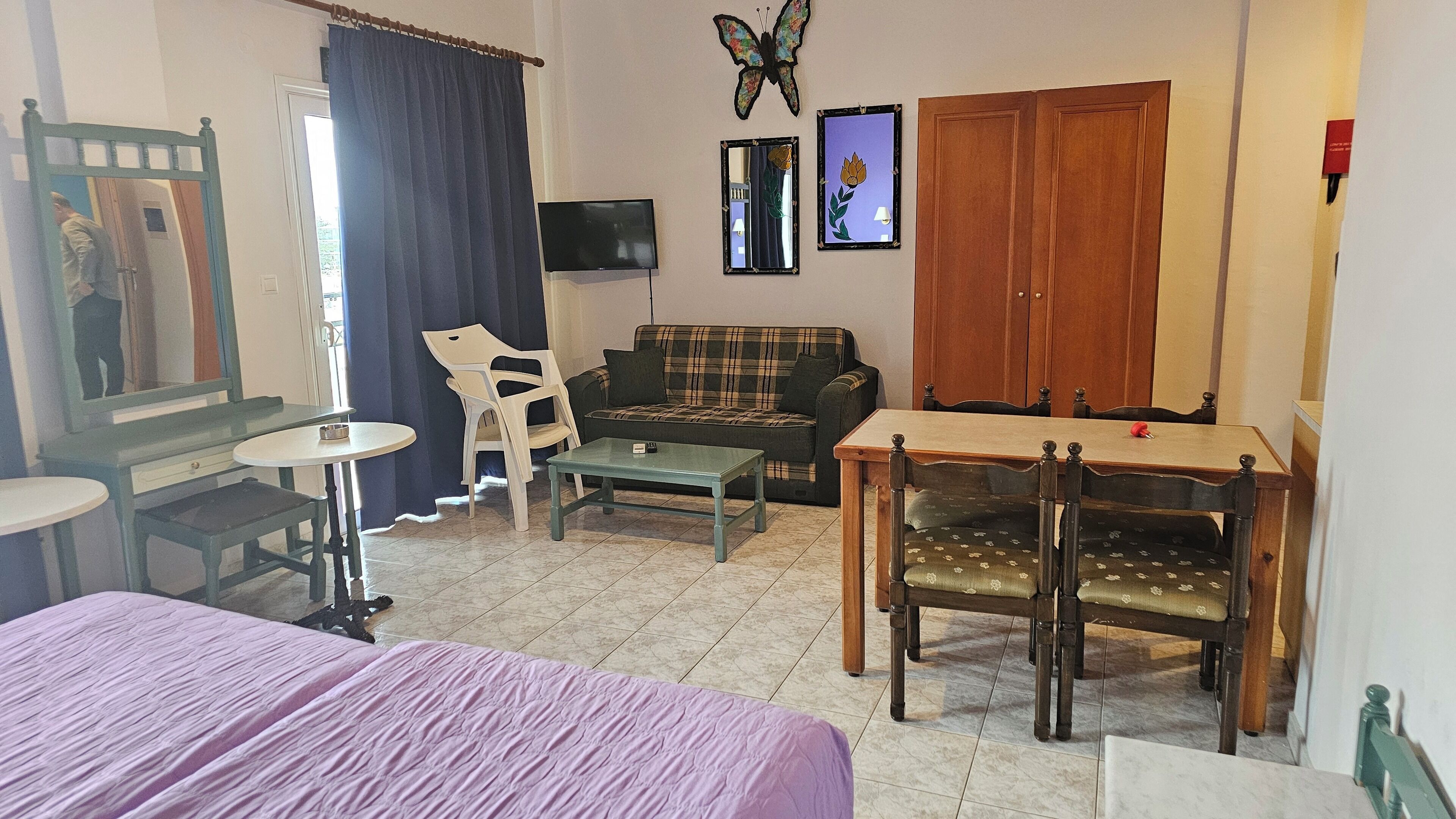 Una habitación con cama, sofá, mesa de comedor y televisor.