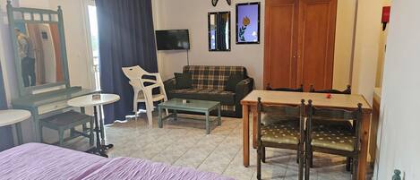 A room with a bed, a sofa, a dining table, and a TV.