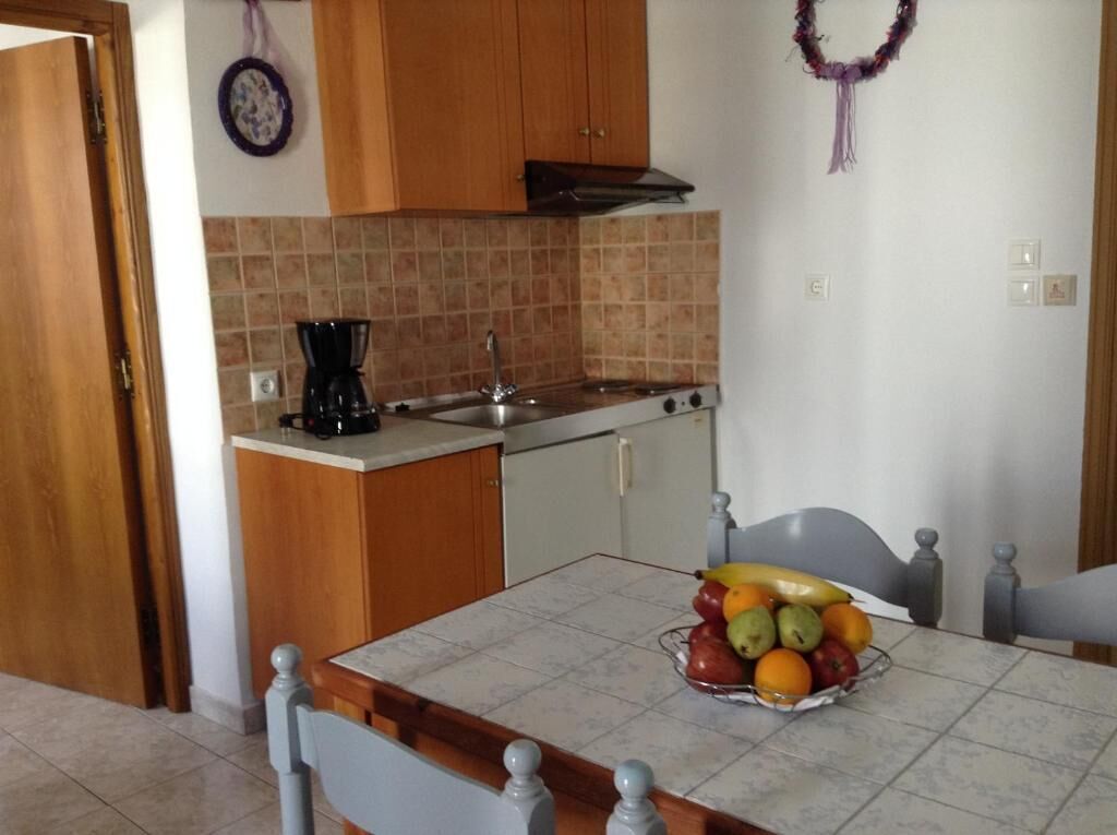 A kitchen with wooden cabinets, a tiled backsplash, a stove, and a fruit bowl on the counter.