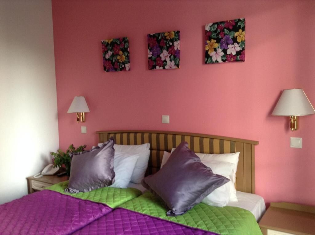 Une chambre à coucher avec un lit, des oreillers, une table de chevet, une lampe et des motifs floraux décorant le mur.