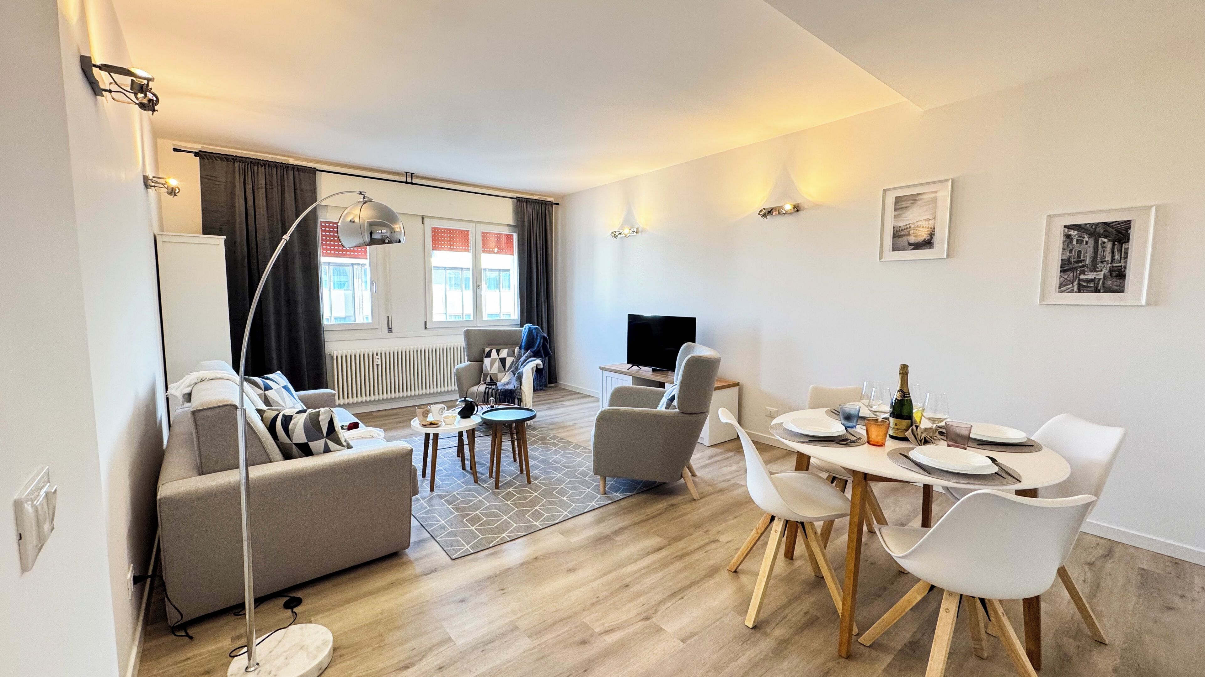 A modern living room with a sofa, TV, and dining area with chairs and a table.