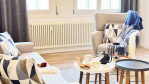 A living room with a sofa, armchair, coffee table, and a radiator.