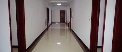 A long, narrow hallway with doors on both sides, leading to a room at the end.