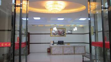 A reception area with a marble counter, a chandelier, and a framed artwork on the wall.