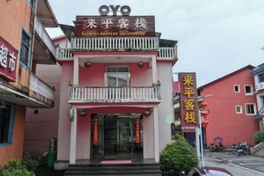 A two-story building with a balcony on the upper floor, a signboard with Chinese characters, and a red door. - Longhushan Laiping Hostel (Guixi)