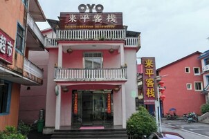 Un edificio de dos pisos con un balcón en el nivel superior, un letrero con caracteres chinos y una puerta roja.