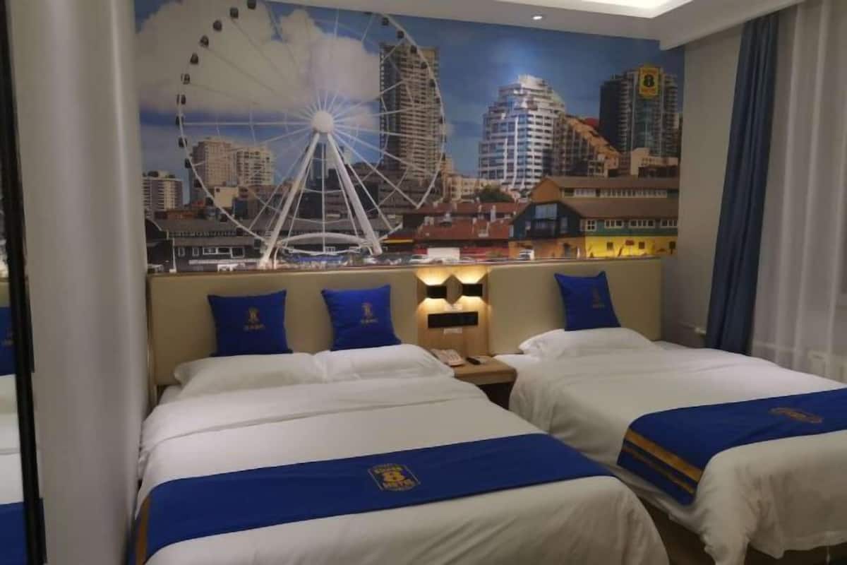A hotel room with two beds, a cityscape mural on the wall, and a city skyline view.