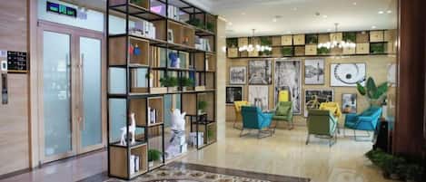 Un hall d’hôtel comprenant un comptoir d’accueil, une grande bibliothèque et un tapis à motifs.