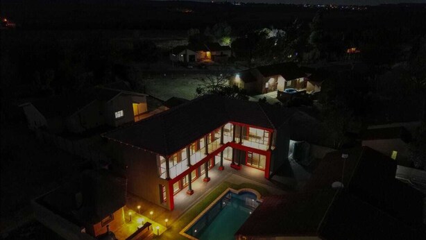 A two-story house with a swimming pool and a well-lit patio area. - Milk and Honey Westonaria (Westonaria)