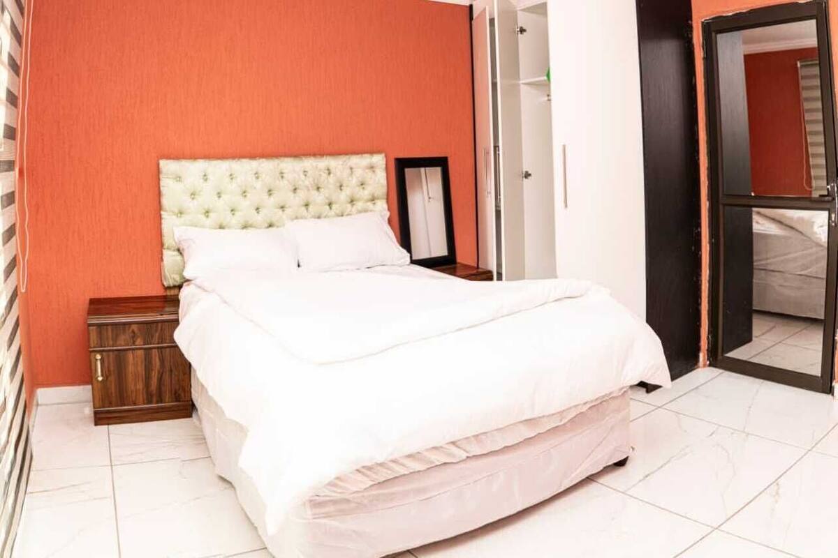 A bedroom with a bed, a nightstand, a wardrobe, and a mirror.