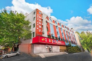 Een hotel met meerdere verdiepingen, met een gevel in rood en blauw, een duidelijke ingang en een heldere lucht.