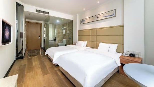 A hotel room with two beds, a bedside table, a chair, a large window, and a painting on the wall. - Guangzhou Dipai Hotel (Nansha Jinzhou) (Guangzhou)