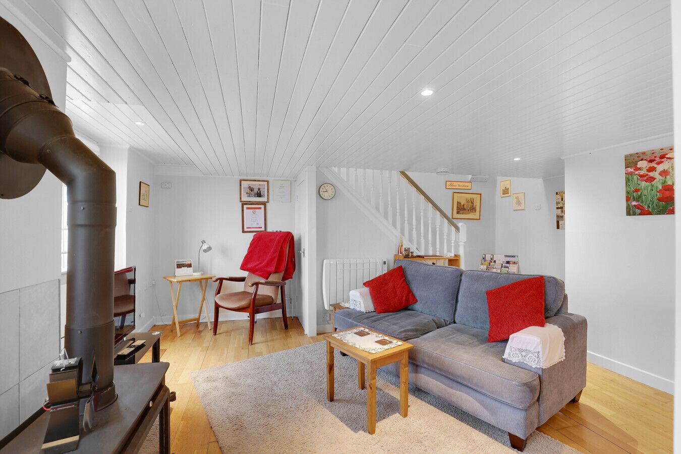 A cozy living room with a sofa, a chair, a table, a radiator, and a wooden floor.