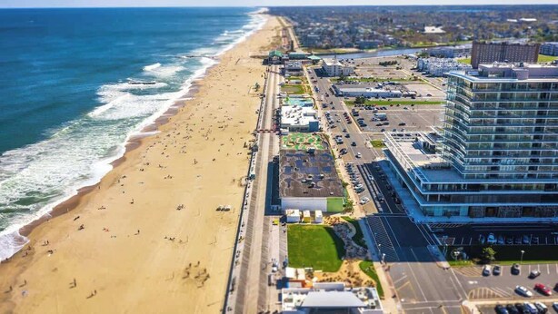 Vista aérea de una ciudad costera con playa, carretera y un moderno complejo de edificios.