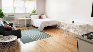 Un dormitorio moderno y bien iluminado con cama, mesitas de noche, un escritorio y una silla.