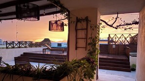 A rooftop terrace with steps leading to a balcony, potted plants, and a view of the sunset. - sunsteps casa holbox  (Isla Holbox)