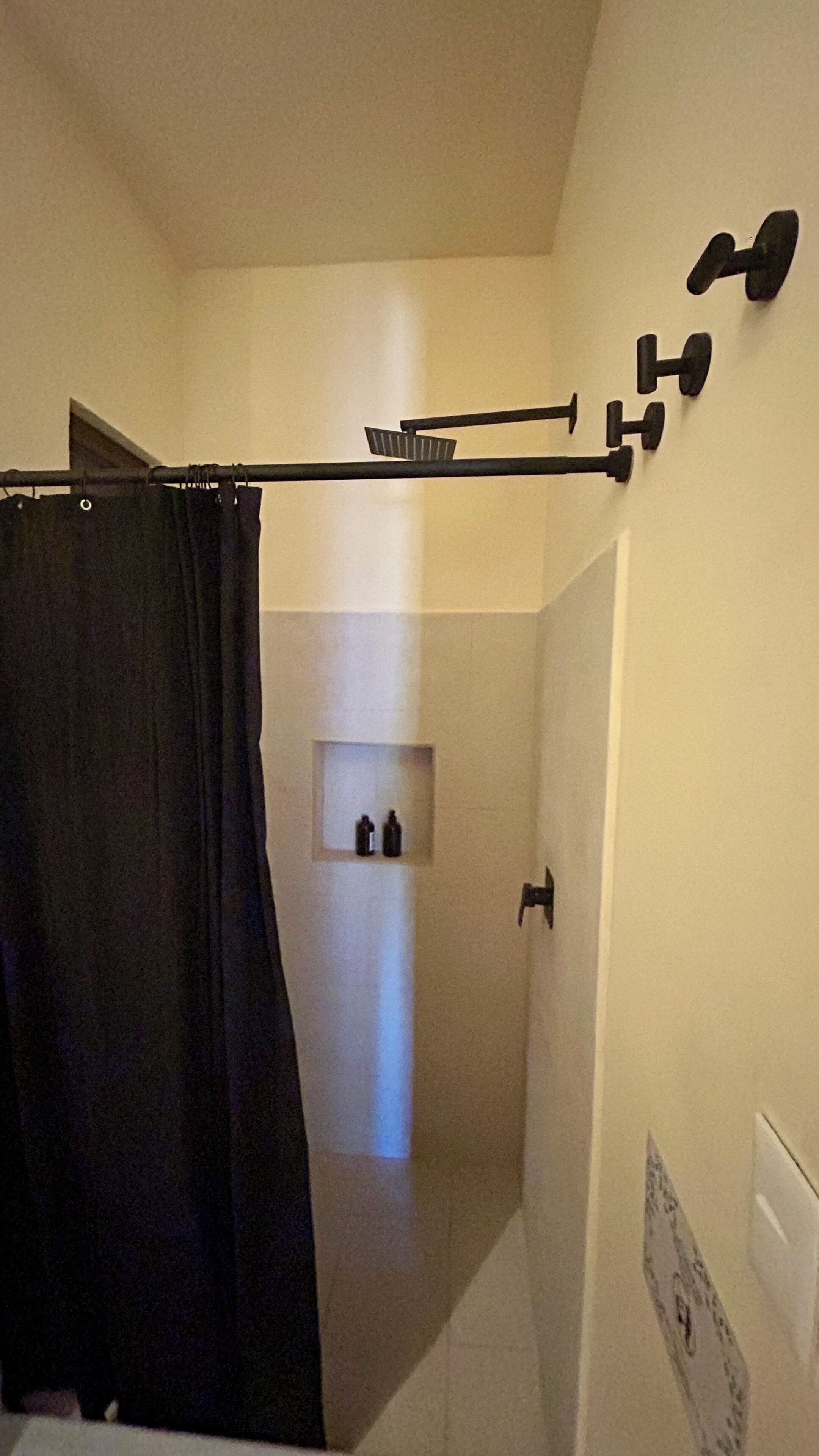Un baño con cortina de ducha, toallero y una toalla colgada en la pared.
