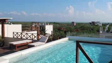 Een buitenzwembad, ligstoelen bij het zwembad