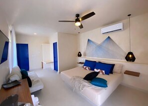 A modern hotel room with a large bed, a desk, a chair, a ceiling fan, and an air conditioning unit. - sunsteps casa holbox  (Isla Holbox)